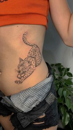 a woman's stomach with a tattoo of a leopard on the side and an orange shirt