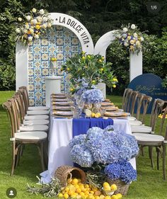 the table is set with blue and yellow flowers, lemons, and greenery