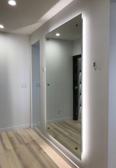 an empty room with a large mirror on the wall and wood flooring in front of it