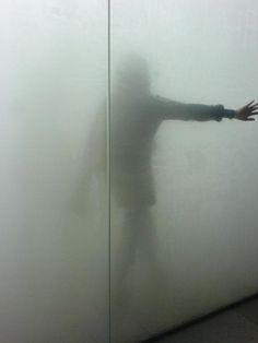 a person standing in front of a white wall with their arms out and shadow on it