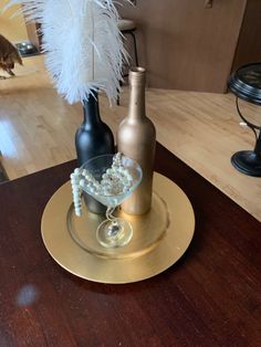 there are two bottles on the table and one is decorated with beads, pearls and a white feather