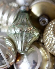 an assortment of silver and gold ornaments are shown in this close up photo, including one glass ornament