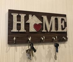 a wooden sign that says home with keys hanging from it's hooks on the wall