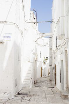 an alley way with white buildings and stairs