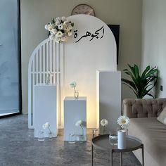 a living room filled with furniture and flowers in vases next to a wall mounted clock