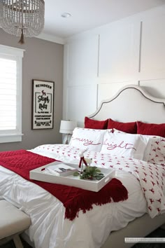 a bed with red and white comforter, pillows and tray on top of it