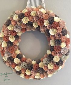 a wreath made out of rolled paper flowers hangs on the wall in front of a door