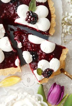 a berry pie with marshmallows and blackberries is on the table next to flowers