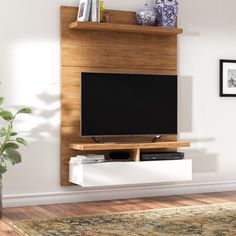 a living room with a television on top of a wooden entertainment center next to a potted plant