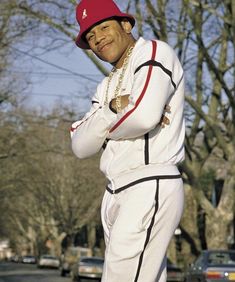 a man standing on top of a skateboard wearing a red hat and white suit