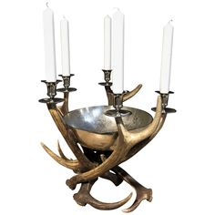 an antler's head and four candles are on a metal bowl with two white candles