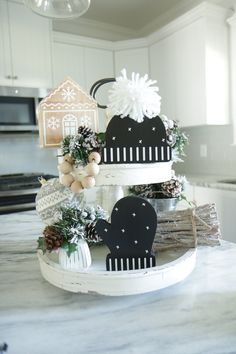 a three tiered cake decorated with black and white decorations on top of a kitchen counter