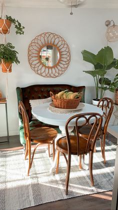 a dining room table with chairs and a bowl of fruit on it's centerpiece