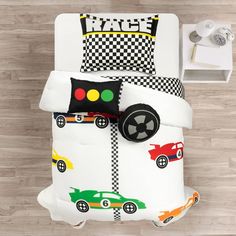 a bed with cars and checkered sheets on it, next to a night stand