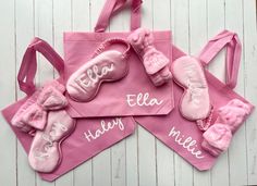 three personalized pink ballet shoes are displayed on a white wooden background with the name ella written on them