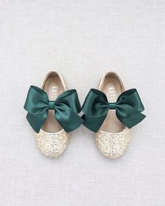 two pairs of green and gold shoes with bows on the front, one is white