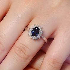 a woman's hand with a diamond and sapphire ring on her finger, showing the center stone