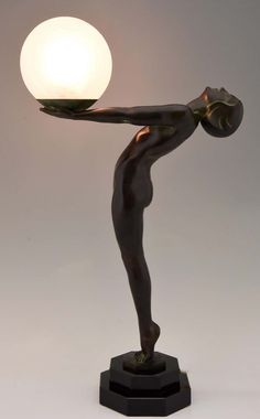 a bronze statue holding a light on top of a table