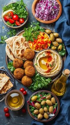 an assortment of food on a platter including pita bread, salad and olives