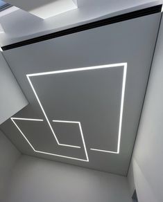 an empty room with some lights on the ceiling and white walls in front of it