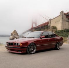 a red car parked in front of the golden gate bridge