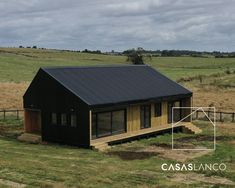 a small black cabin sitting on top of a lush green field