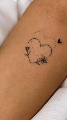 a heart shaped tattoo with flowers on the left side of the arm, and a dotted dot in the middle