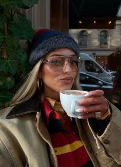 a woman wearing glasses drinking from a cup