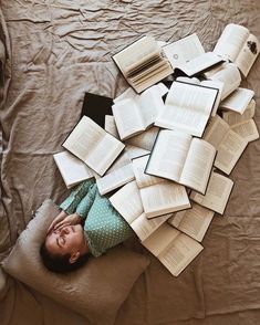 a baby laying on top of a bed covered in books