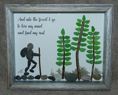 a shadow frame with an image of a person holding a stick and some rocks on the ground