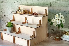 a set of three wooden shelves sitting on top of a table next to a potted plant