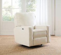 a white recliner chair sitting in front of a window with an arm rest on top of it