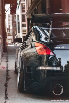 the back end of a black car parked in front of a tall building