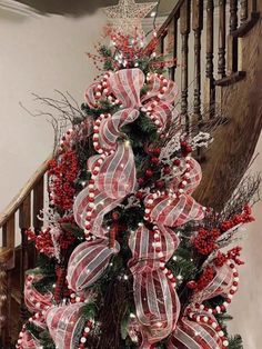 a christmas tree with red, white and silver decorations on it in front of a banister