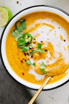 a white bowl filled with carrot soup and garnished with cilantro