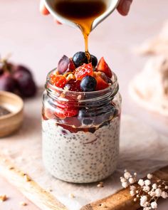 someone pouring dressing into a jar filled with fruit