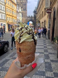 a hand holding an ice cream cone with chocolate sprinkles on the top