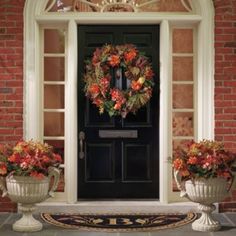 the front door is decorated with wreaths and flower potted plants on either side