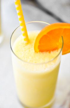 an orange slice is sitting on top of a smoothie in a glass with a straw