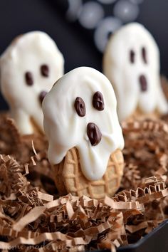 three cookies with white frosting and chocolate sprinkles in the shape of ghost faces