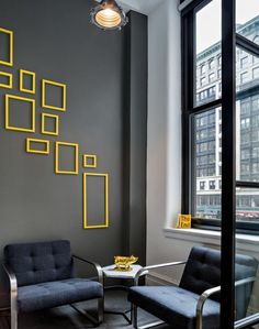 a living room with two chairs and a coffee table in front of a wall that has yellow squares on it