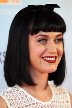 a close up of a person wearing a white dress and a black bow on her head