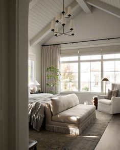 a large bed sitting under a window next to a white couch in a living room