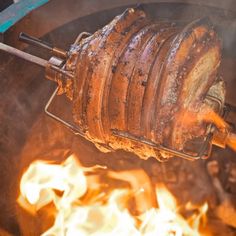 a large piece of meat is being cooked over an open fire