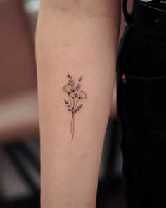 a small flower tattoo on the left arm