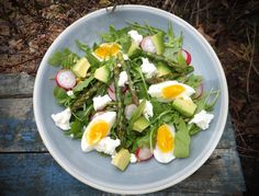 a salad with eggs, asparagus and radishes in a blue bowl