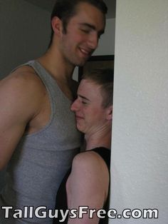 a man and woman standing next to each other in front of a white wall with the words tall guys free com written on it