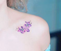 a close up of a woman's shoulder with purple flowers on her left side