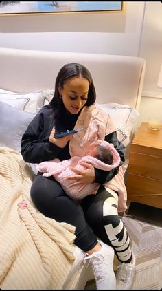 a woman sitting on a bed holding a baby