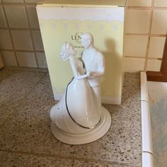 a white figurine sitting on top of a counter next to a box